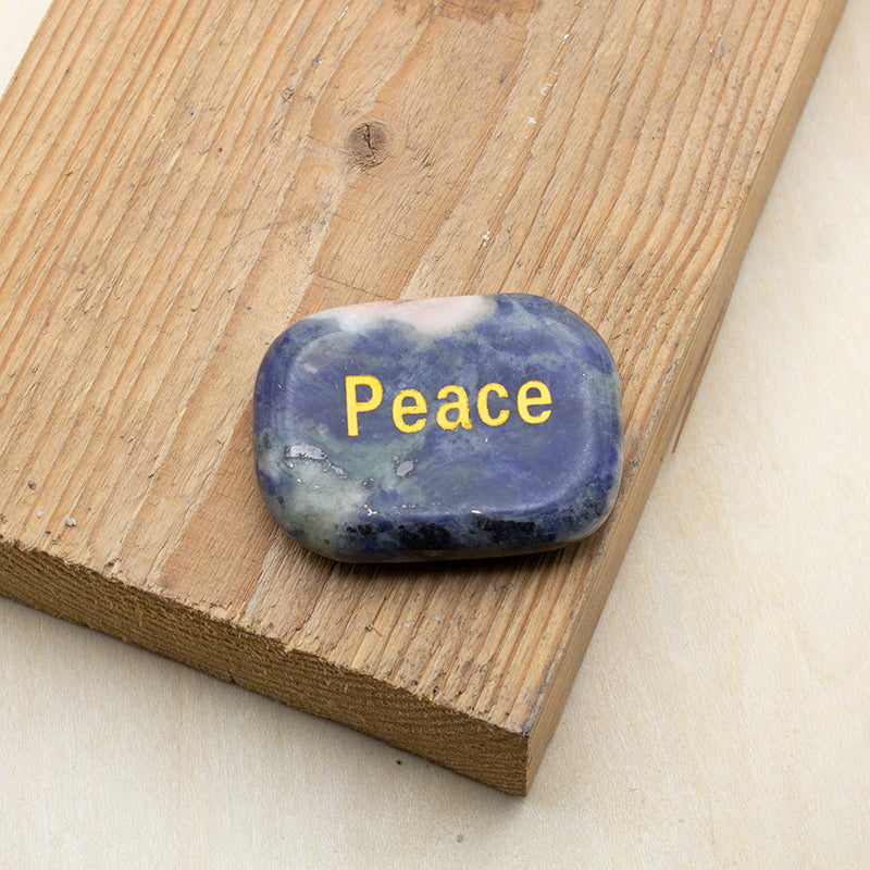 Piedra de los deseos paz de lapislázuli natural con palabra PEACE grabada en dorado.