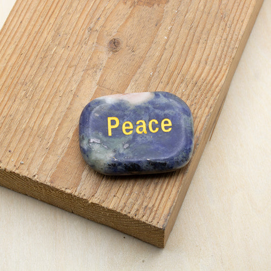Piedra de los deseos paz de lapislázuli natural con palabra PEACE grabada en dorado.