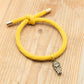 Pulsera costalero cristiana amarilla con cordón elástico y colgante de costalero para Semana Santa