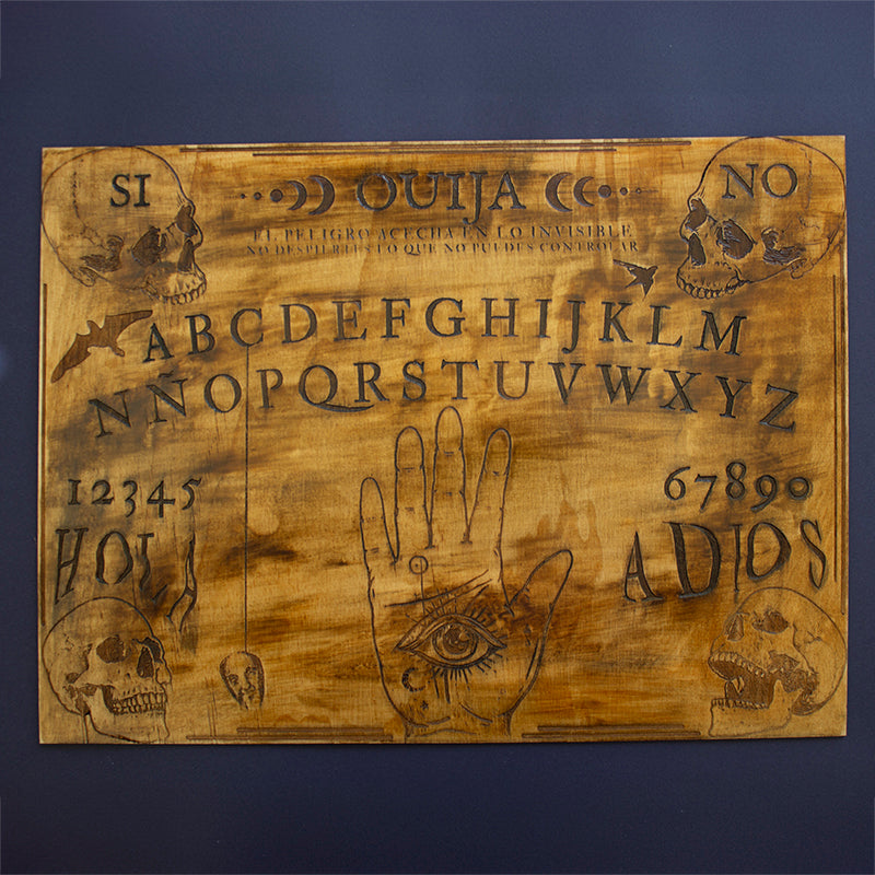 Tabla de Ouija artesanal de madera pintada a mano con dedal en forma de calavera, ideal para sesiones espirituales y rituales esotéricos.